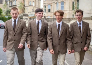 four male Norland nannies in uniform walking down the street