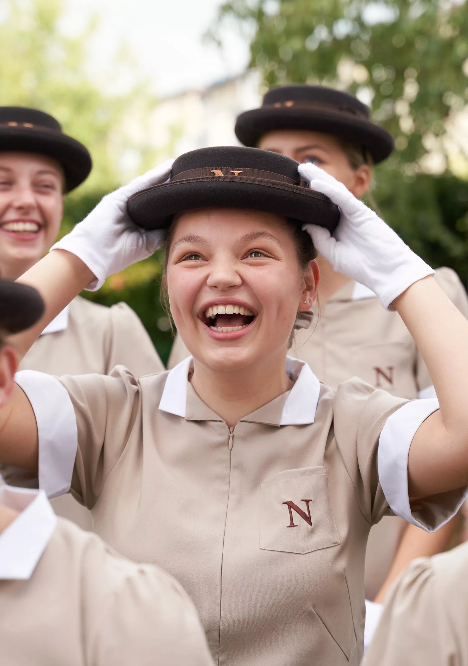 a female Norland Nanny student adjusting her hat smiling