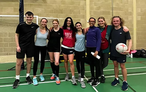 a group of men and women in sports attire holding a netball in a sports hall